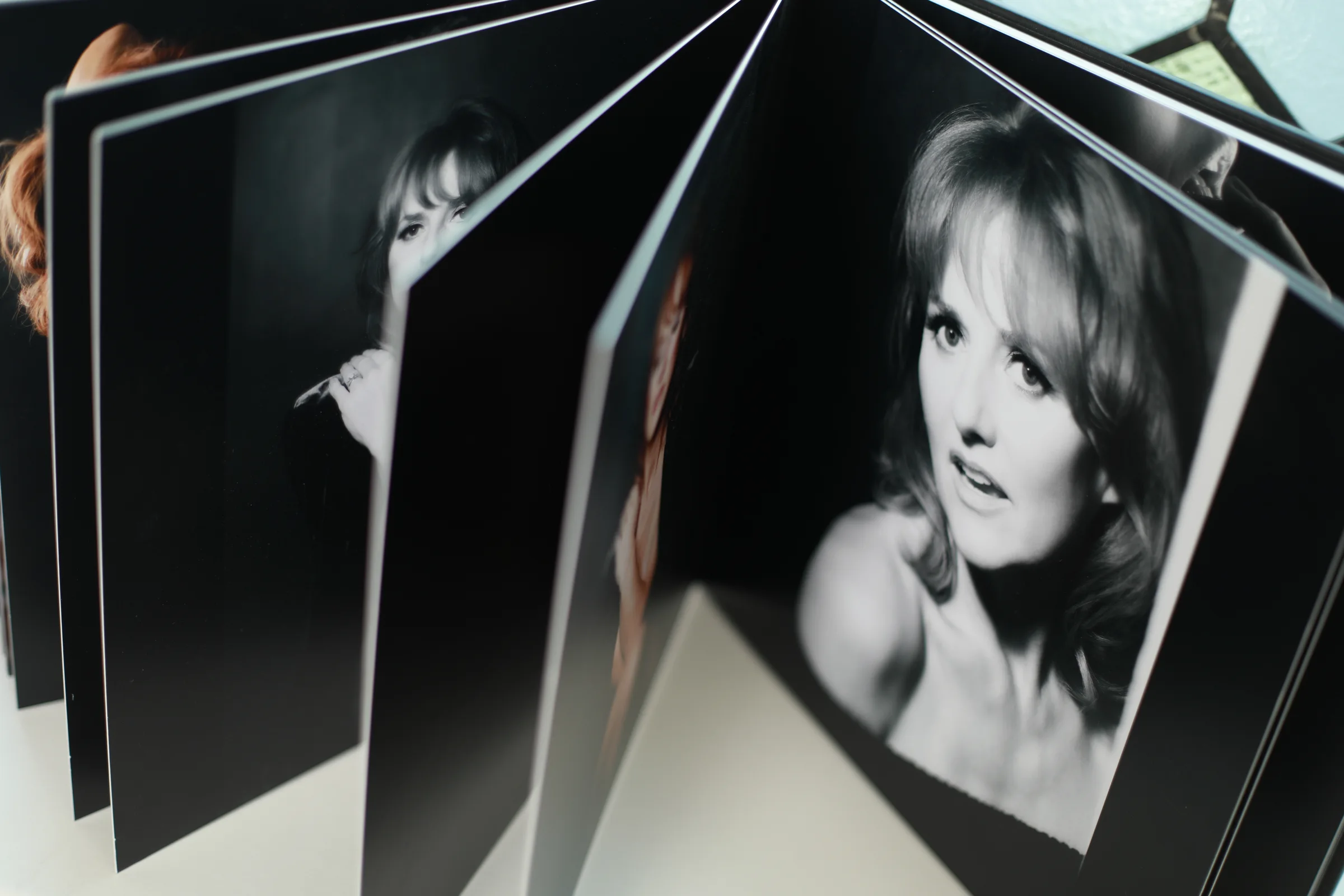 The pages of a Divine Divas album standing open to show black and white portraits