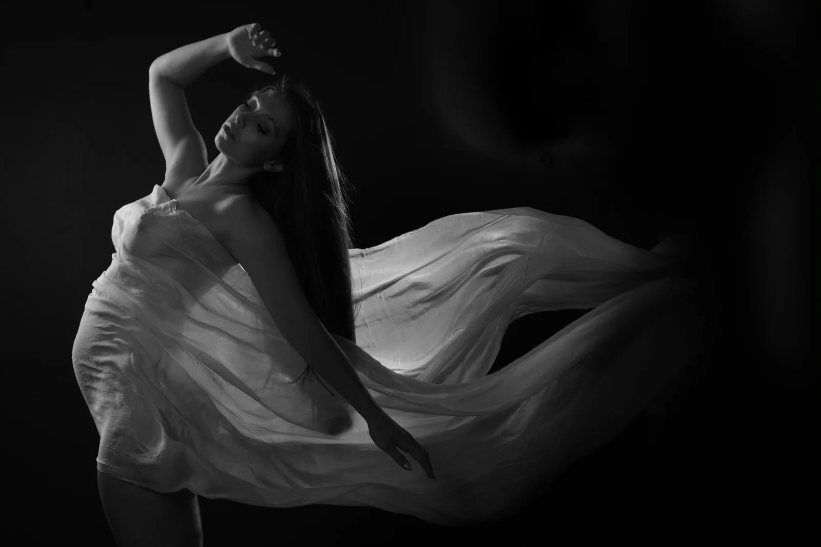 A client seated in a flowing white dress in a black and white portrait