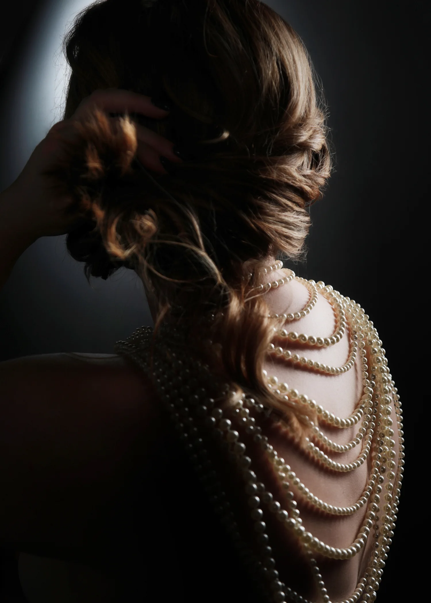 A client with her hair pinned up and pearl necklaces draped down her back