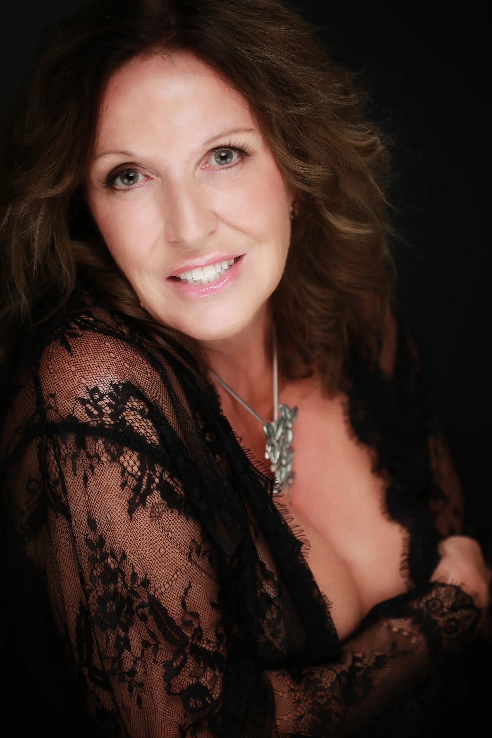 The same client smiling at the camera in black lace and a silver necklace