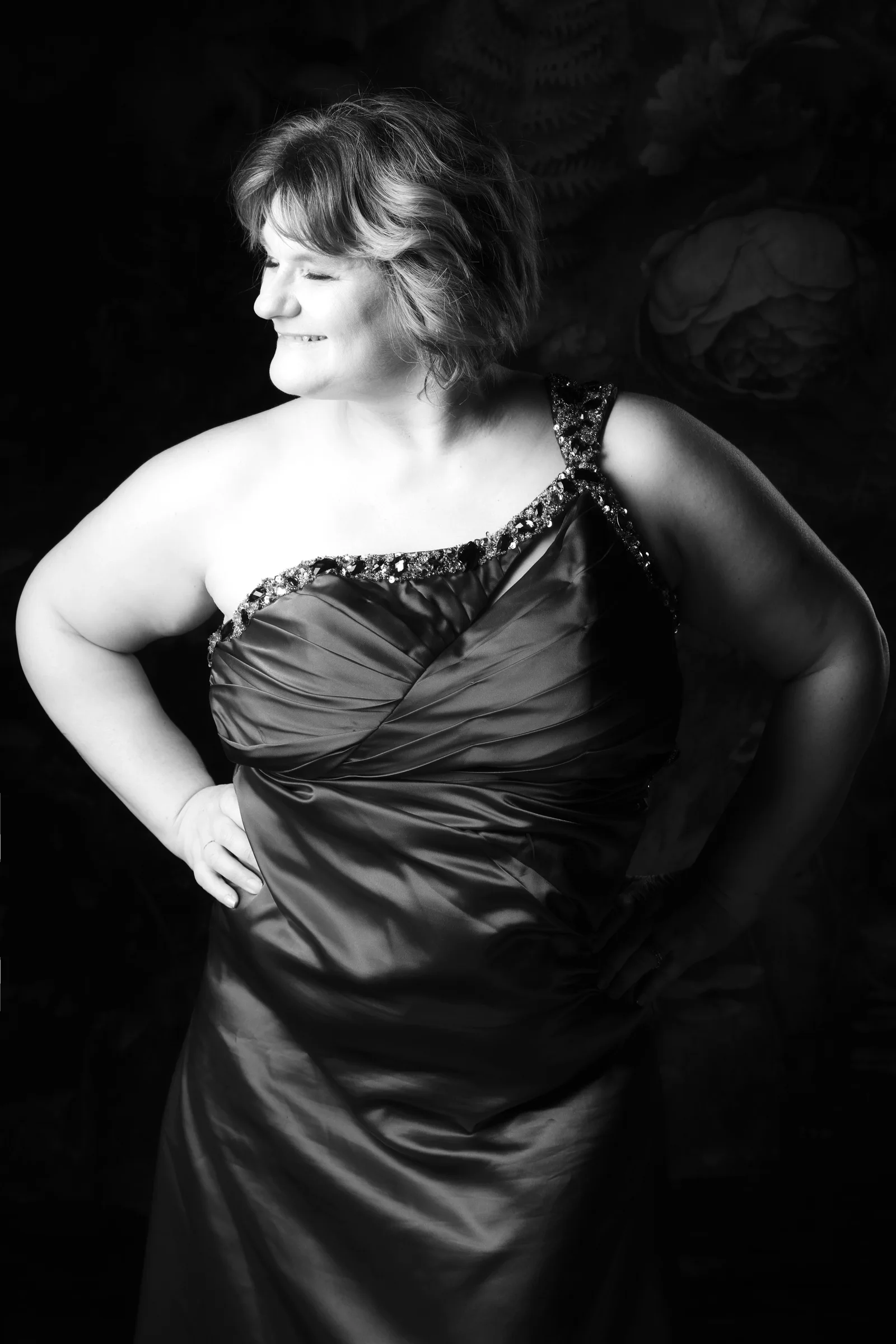 The same client smiling in her finished black evening-dress portrait